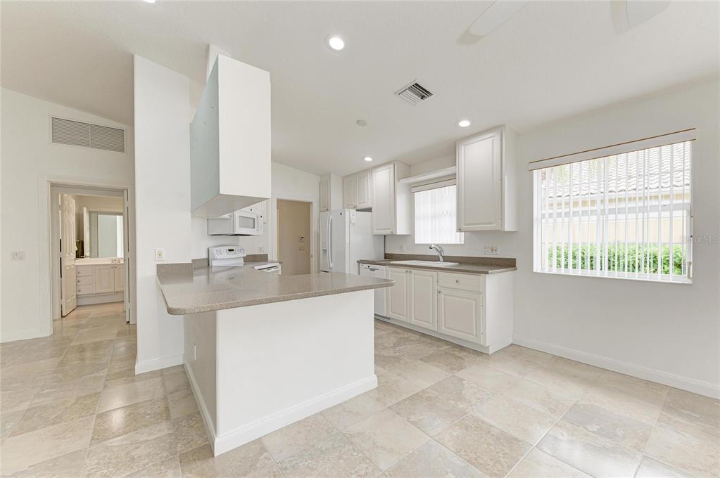 6073 Erice Street Venice, FL 34293 - Photo 13 of 71 a large white kitchen with cabinets and a window