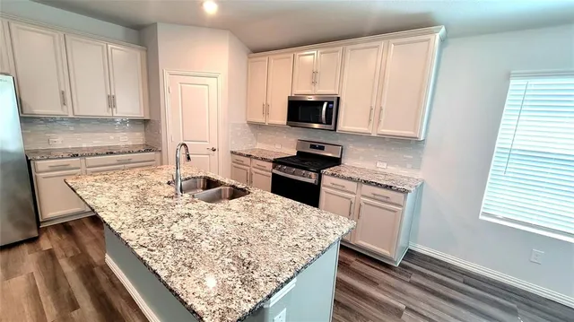 a kitchen with stainless steel appliances kitchen island granite countertop a stove a sink dishwasher and a refrigerator