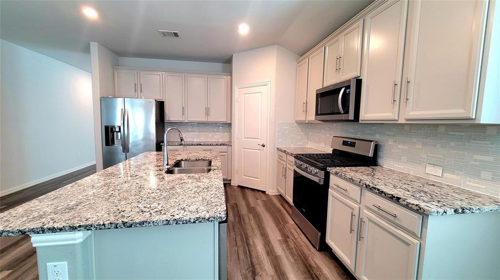 263 Sunshine Lane Lavon, TX 75166 - Photo 15 of 27 a kitchen with kitchen island granite countertop stainless steel appliances and white cabinets