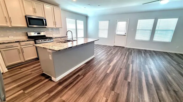 a view of an empty room with wooden floor and fan