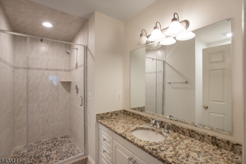 14 Locust Street Madison, NJ 07940 - Photo 25 of 33 a bathroom with a granite countertop sink a mirror and a shower