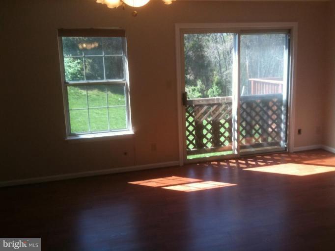 21673 Hazelnut Square, Unit 172 Sterling, VA 20164 - Photo 10 of 15 an empty room with wooden floor and windows