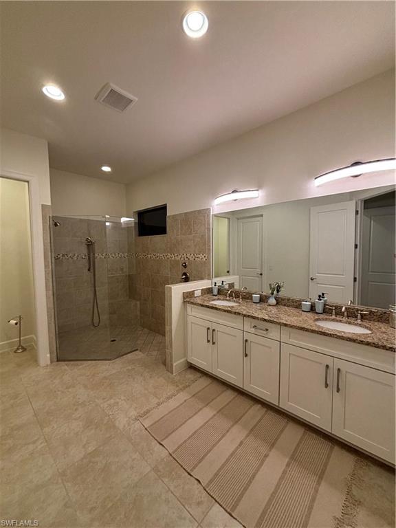9571 Mussorie Court Naples, FL 34114 - Photo 14 of 26 a large bathroom with a large mirror vanity and shower