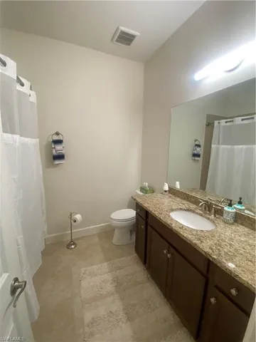 a bathroom with a granite countertop sink a toilet and a mirror