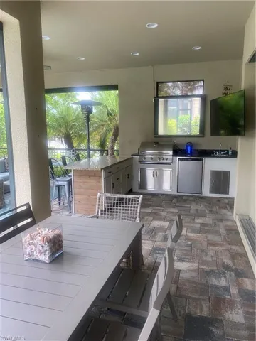 a living room with stainless steel appliances furniture a flat screen tv and floor to ceiling window