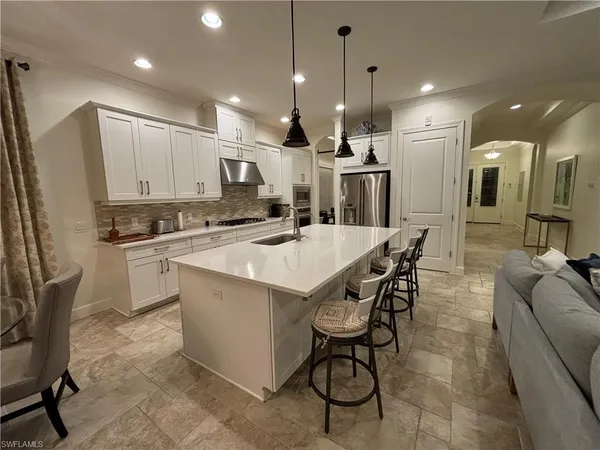 a kitchen with stainless steel appliances kitchen island granite countertop a sink and a refrigerator
