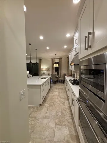 a large white kitchen with a stove a sink dishwasher and a oven