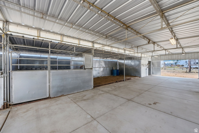 3732 Campbell Road Tooele, UT 84074 - Photo 57 of 69 Covered equestrian facility featuring multiple stalls with metal gates, an open concrete aisle, and a corrugated metal roof structure
