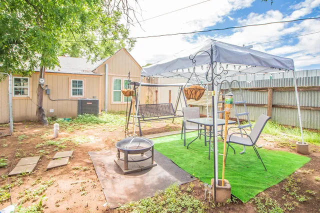 a view of a patio with chairs and a table and chairs under an umbrella