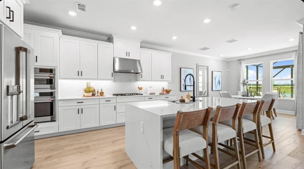 13618 Cornerstone Way Parrish, FL 34219 - Photo 6 of 27 a kitchen with stainless steel appliances granite countertop a table chairs microwave and cabinets