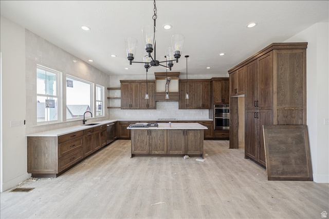 7189 South Sage Road, Unit 214 West Jordan, UT 84081 - Photo 10 of 29 Spacious kitchen featuring extensive wood cabinetry, a large center island with a cooktop, integrated double ovens, and a window bank offering natural light