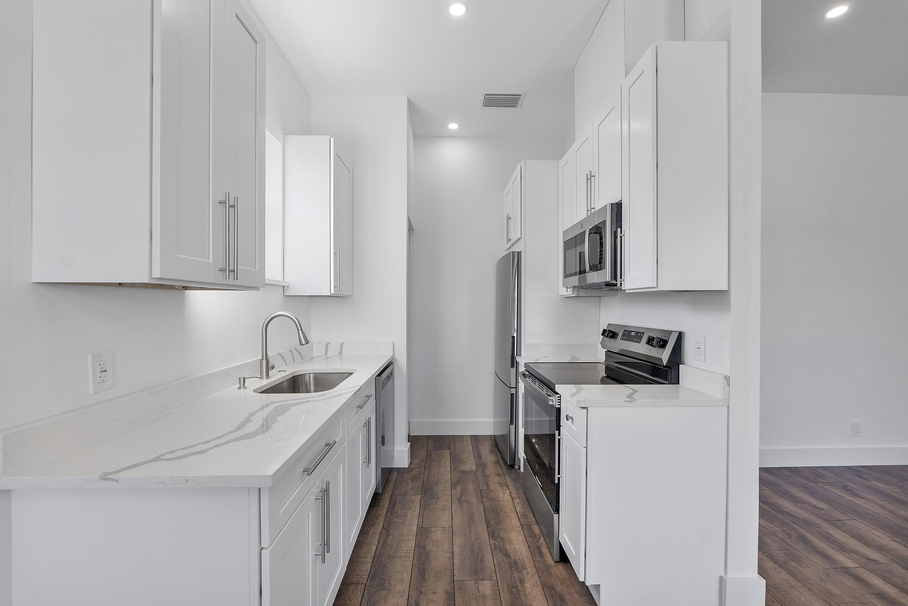 1573 West 16th Street Riviera Beach, FL 33404 - Photo 8 of 23 a kitchen with stainless steel appliances a sink stove top oven and white cabinets