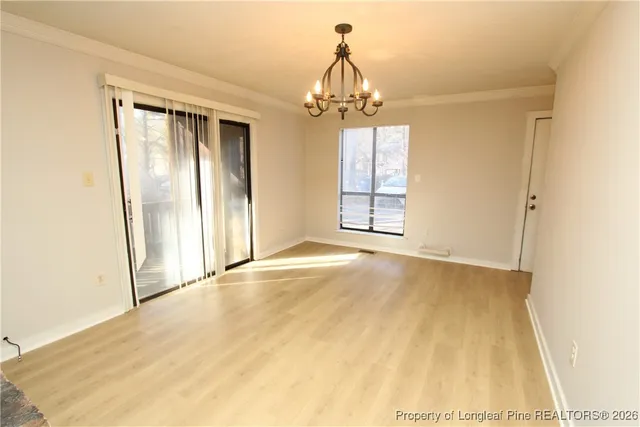 an empty room with chandelier fan and windows