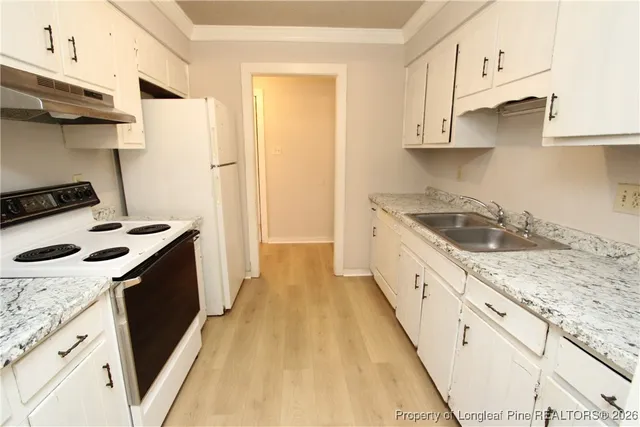 a kitchen with granite countertop a sink a stove and refrigerator