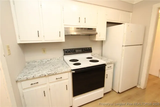 a kitchen with granite countertop white cabinets and white appliances