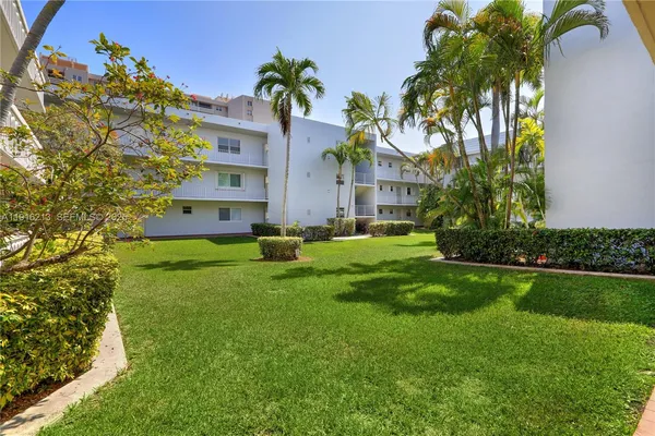 a front view of multi story residential apartment building with yard and green space