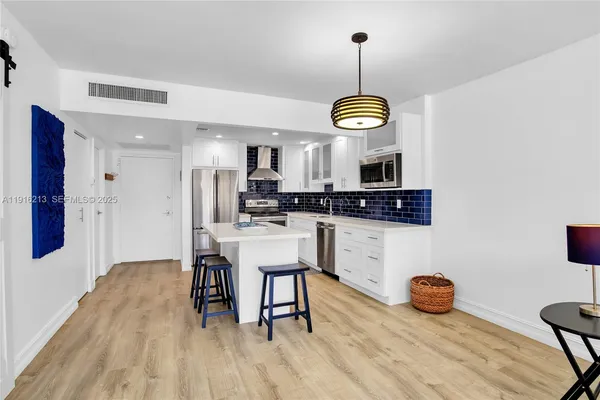 a kitchen with stainless steel appliances granite countertop a stove a sink a refrigerator and a wooden floor