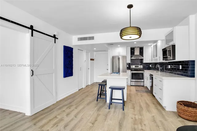 a view of a kitchen with stainless steel appliances granite countertop a stove a refrigerator and a wooden floor