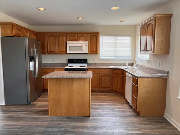 a kitchen with stainless steel appliances granite countertop a stove a sink dishwasher a refrigerator and a microwave oven with wooden floor