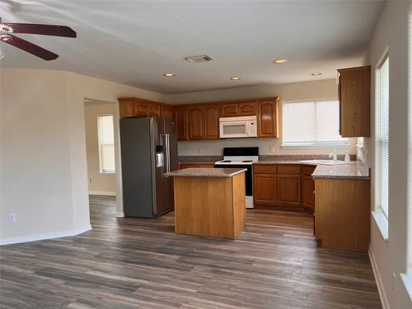 a kitchen with granite countertop a refrigerator stove top oven and sink