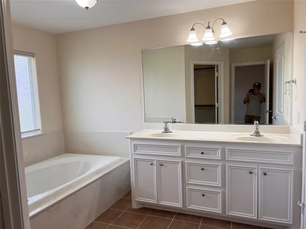 a bathroom with a tub a double vanity sink and a mirror