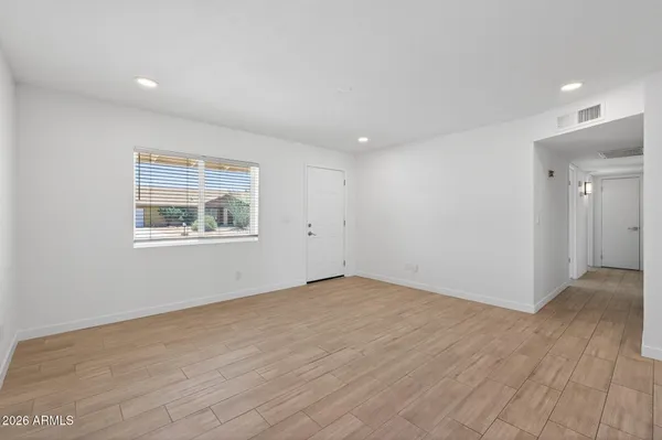 an empty room with wooden floor and window