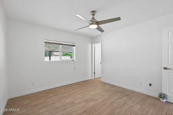 an empty room with wooden floor ceiling fan and windows