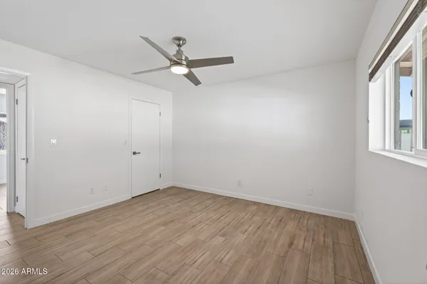an empty room with wooden floor ceiling fan and windows
