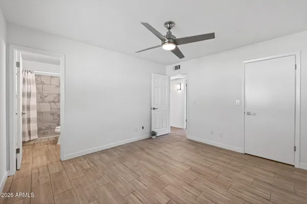 an empty room with wooden floor fan and windows