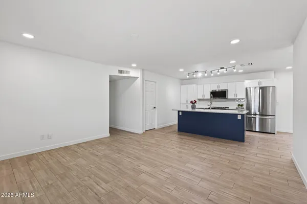 a large kitchen with stainless steel appliances granite countertop a stove top oven a sink dishwasher and a refrigerator with wooden floor