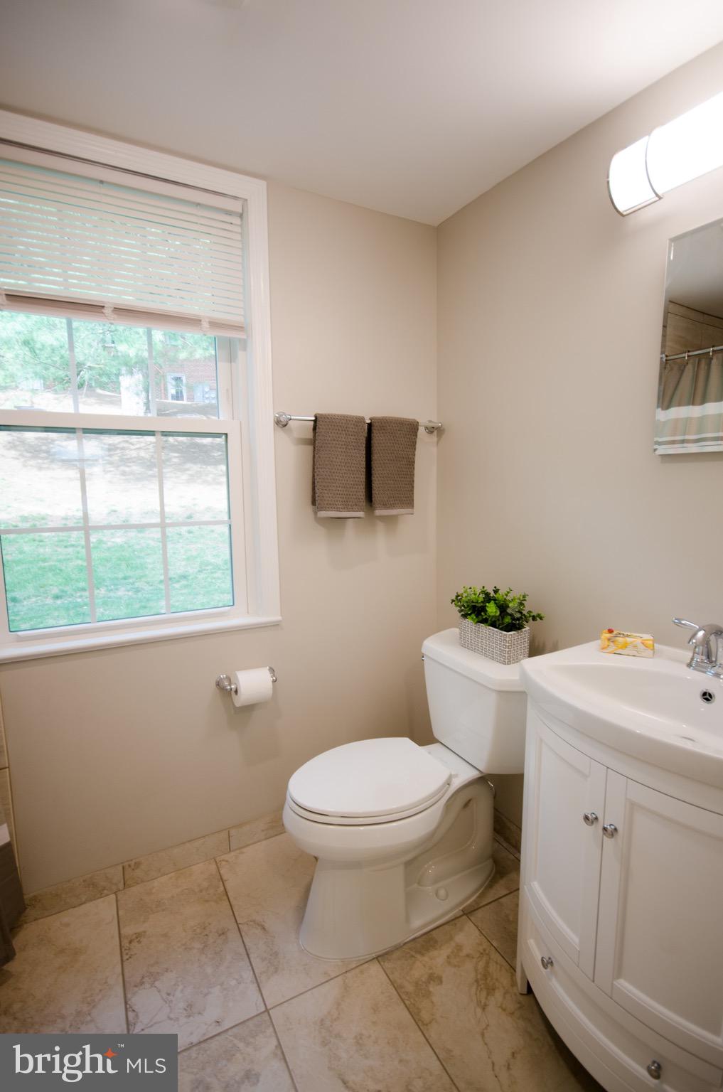 8201 Grubb Road, Unit 101 Silver Spring, MD 20910 - Photo 14 of 31 a bathroom with a toilet a sink a window and mirror