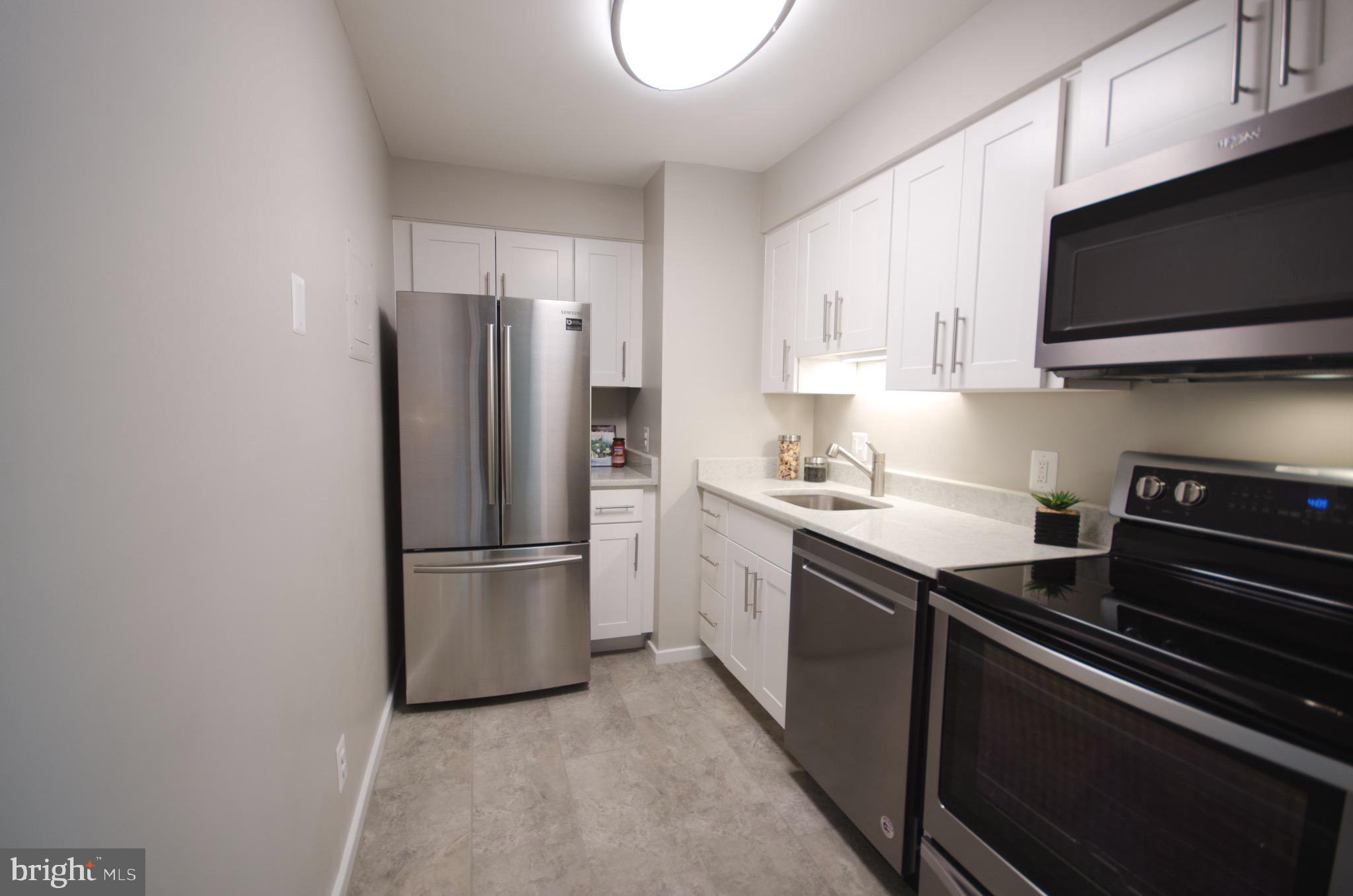 8201 Grubb Road, Unit 101 Silver Spring, MD 20910 - Photo 8 of 31 a kitchen with stainless steel appliances a refrigerator stove and microwave