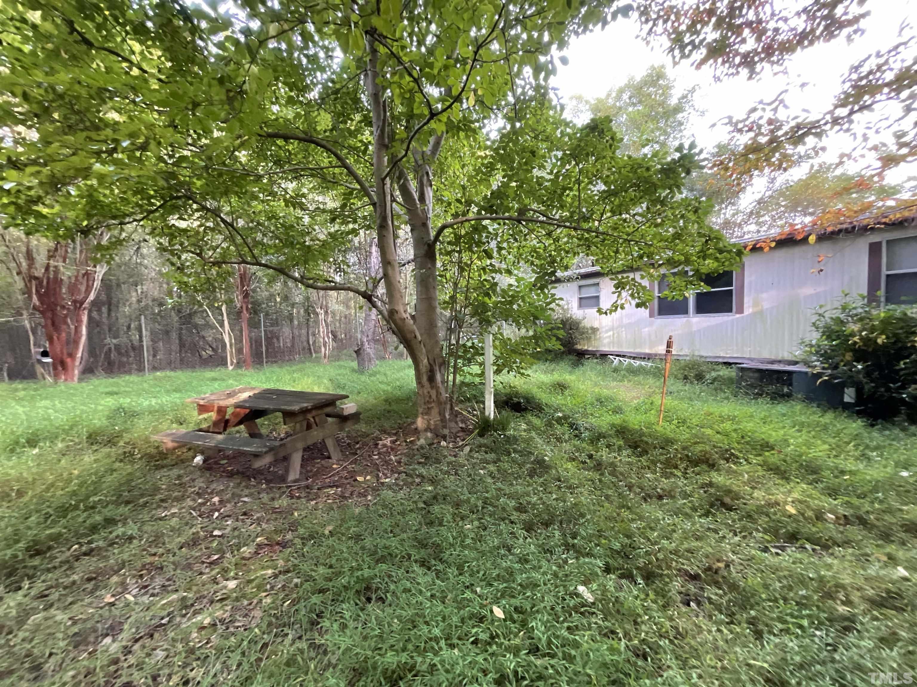 8229 Holly Springs Road Raleigh, NC 27606 - Photo 12 of 24 a view of a backyard with table and chairs and a large tree