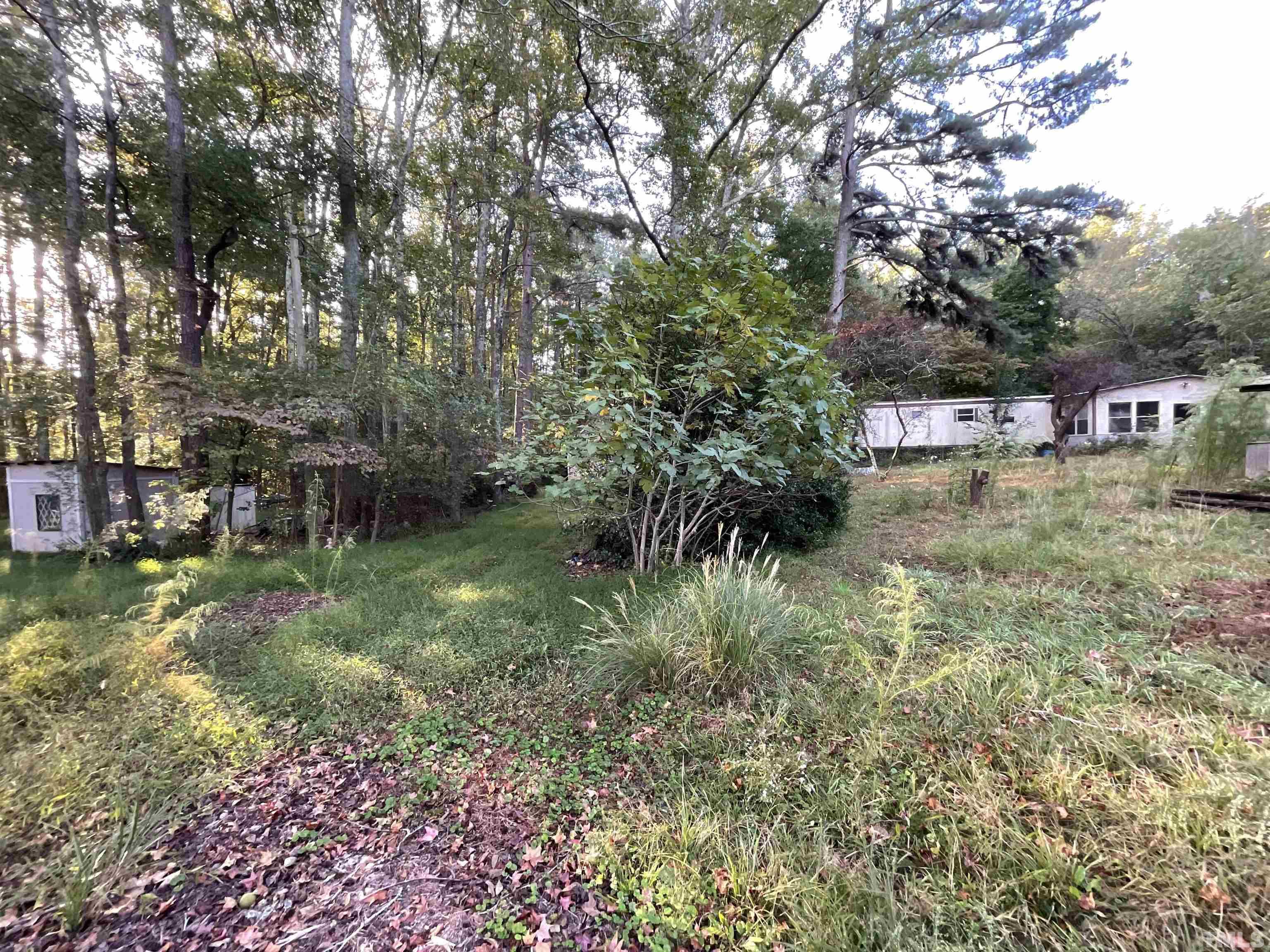 8229 Holly Springs Road Raleigh, NC 27606 - Photo 16 of 24 a view of a yard with plants and a bench