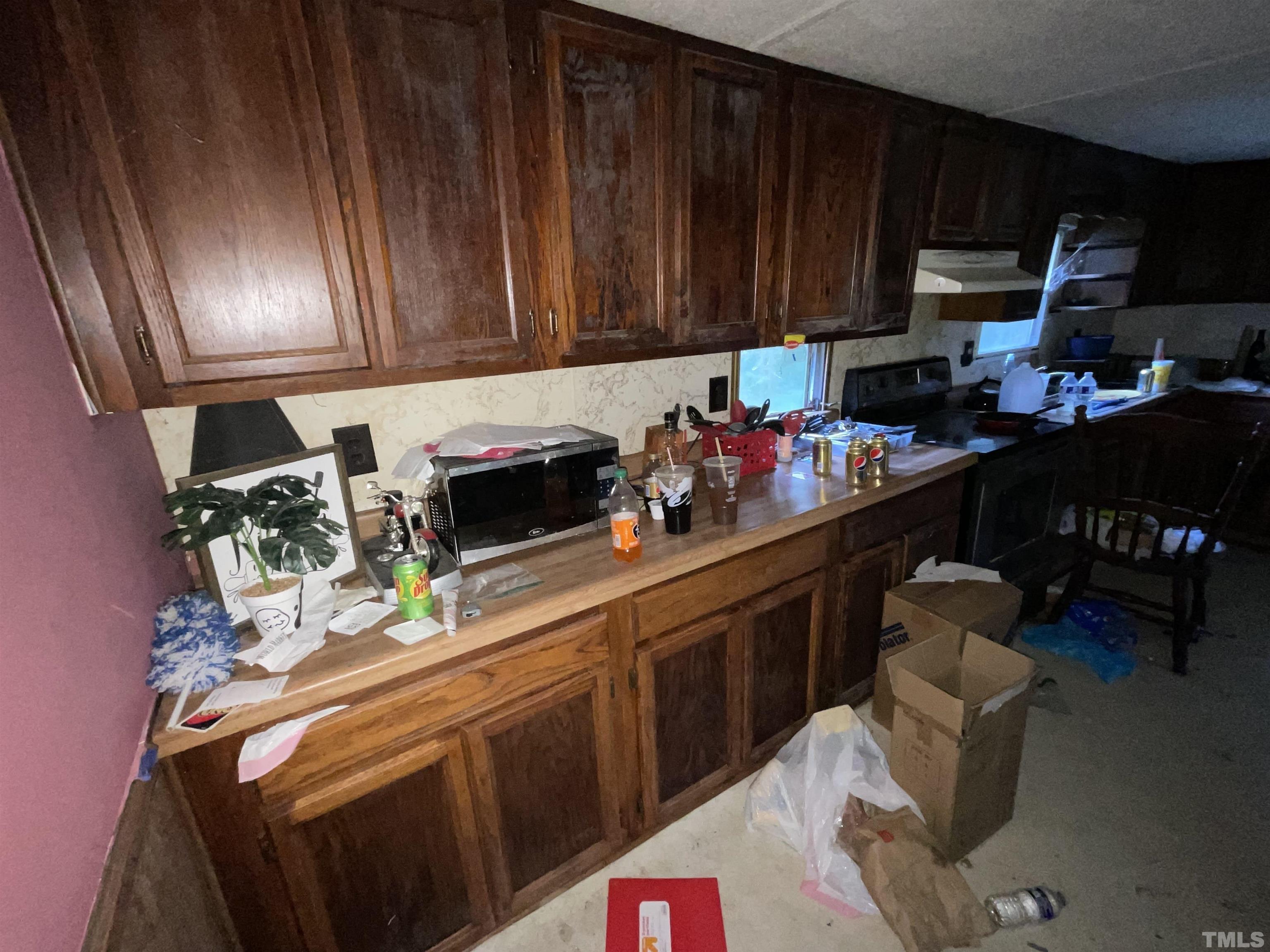 8229 Holly Springs Road Raleigh, NC 27606 - Photo 23 of 24 a kitchen with granite countertop lots of clutter and cabinets