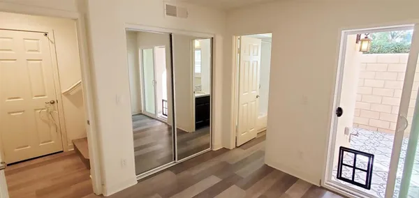 an empty room with wooden floor front door and windows