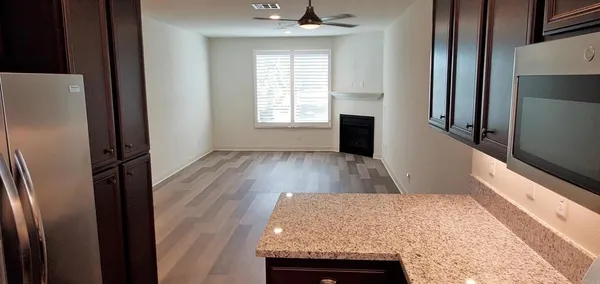 a view of a livingroom with wooden floor and a kitchen space