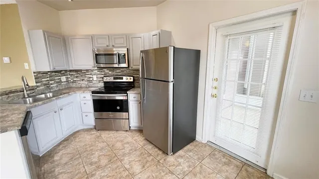 a kitchen with stainless steel appliances granite countertop a refrigerator and a sink