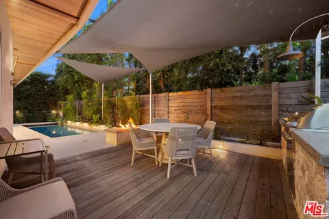 a view of a roof deck with table and chairs with wooden floor and fence