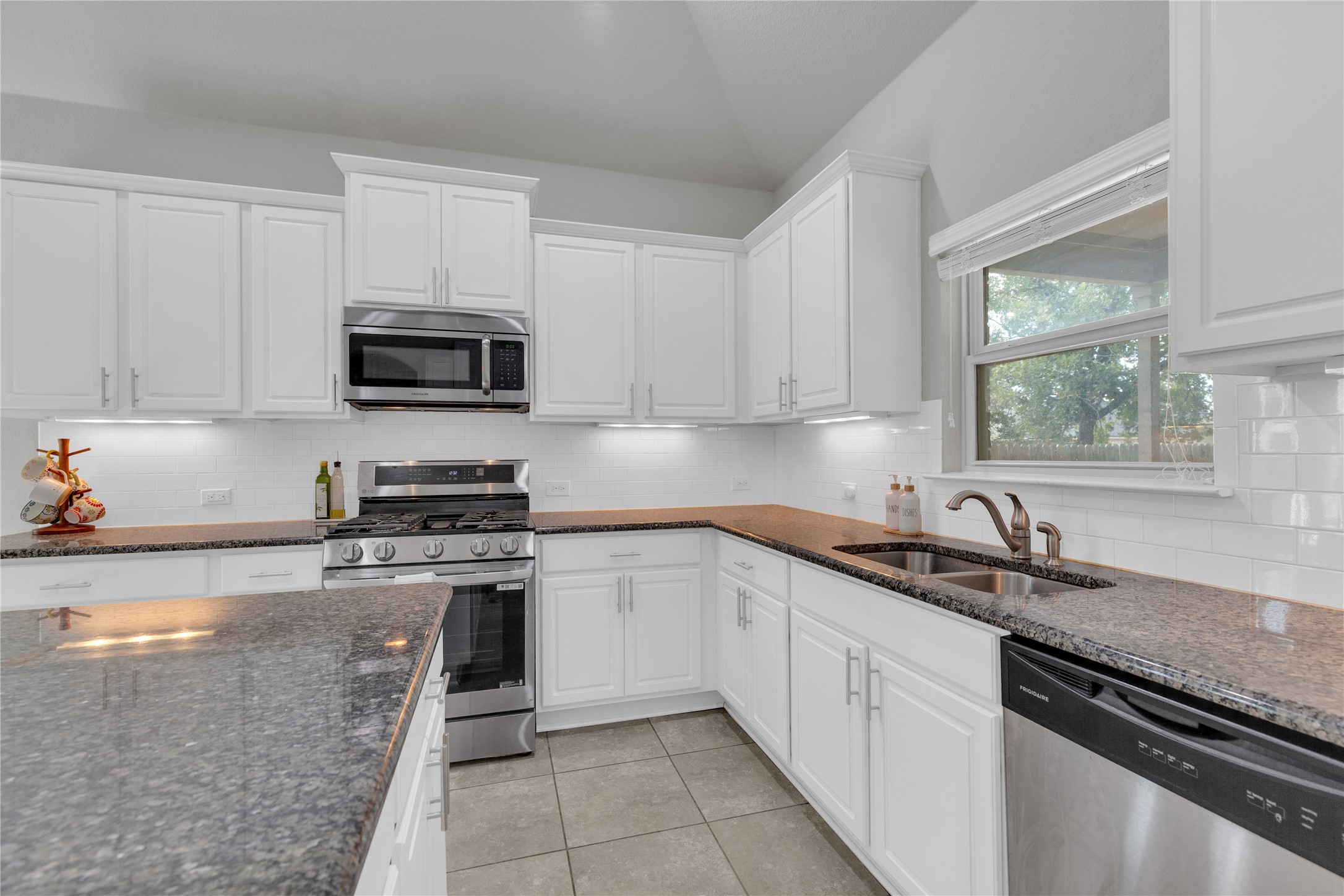 721 Schefer Street Leander, TX 78641 - Photo 13 of 38 a kitchen with granite countertop a sink a stove top oven and cabinets