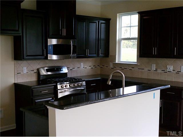 1311 Rodessa Run Raleigh, NC 27607 - Photo 3 of 4 a kitchen with granite countertop a sink a stove a microwave and cabinets