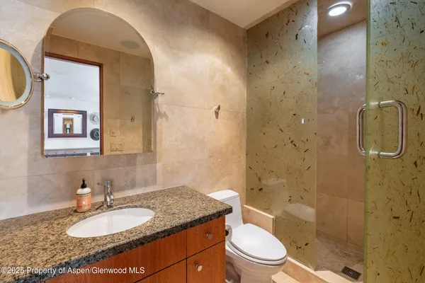 a bathroom with a granite countertop sink toilet and shower