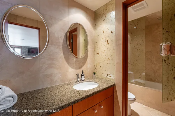 a bathroom with a granite countertop double vanity sink mirror and shower