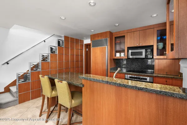a kitchen with stainless steel appliances granite countertop a chairs a sink and a microwave