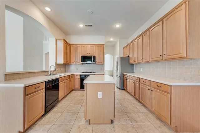 a large kitchen with stainless steel appliances lots of white cabinets