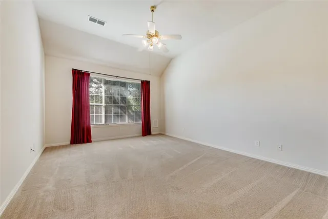 en empty room with windows and ceiling fan