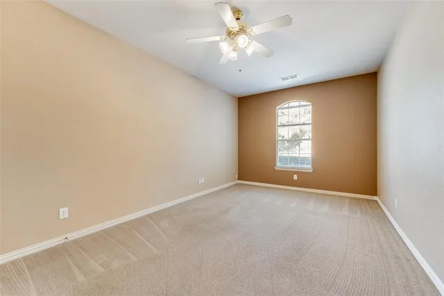 an empty room with windows and ceiling fan