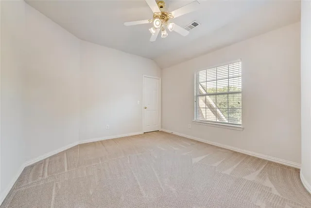 an empty room with a chandelier fan and windows