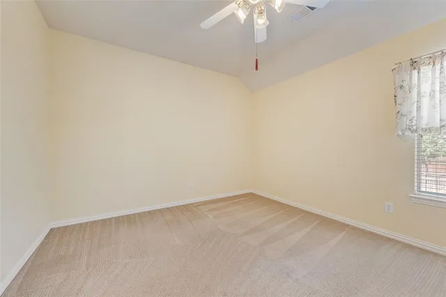 an empty room with a chandelier fan and windows