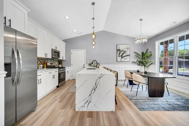 a living room with stainless steel appliances kitchen island granite countertop furniture wooden floor and a view of kitchen